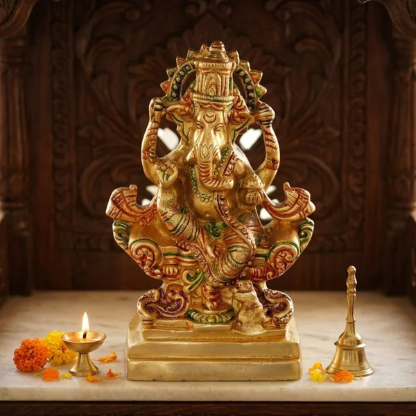 Brass Ganesh idol, 6.8 inch, on the marble shelf of a carved wooden home temple with a lit diya and bell