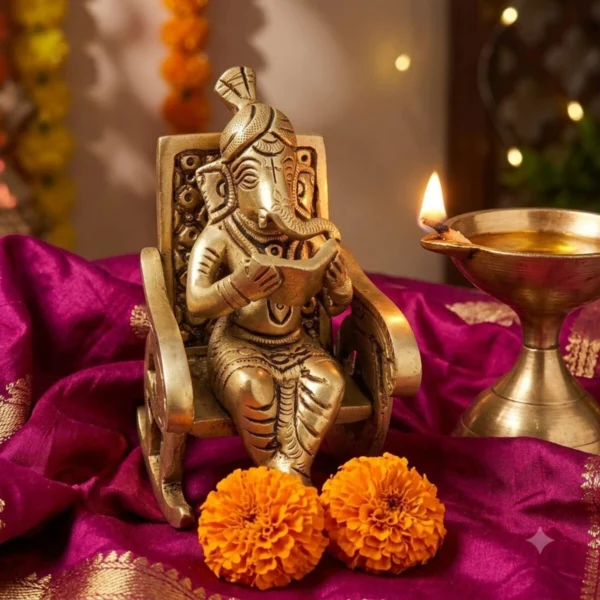 Brass reading Ganesh statue on magenta silk with a brass diya for Diwali